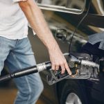 Handsome man pours gasoline into tank of car